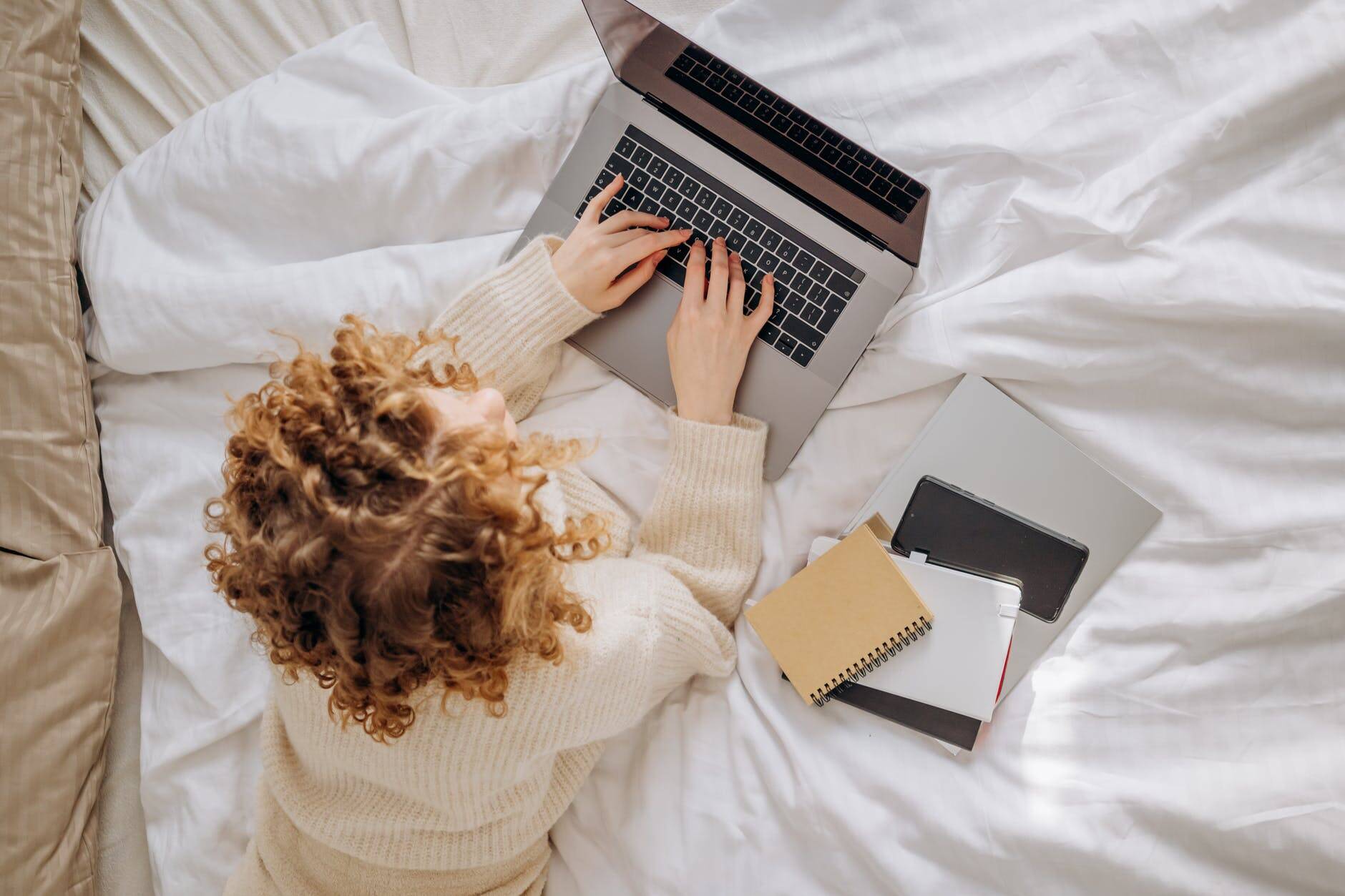 Frau liegt auf Bett am Notebook